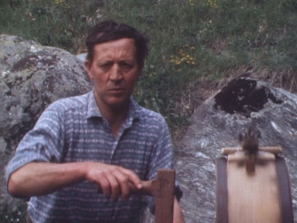 Paysan utilisant une baratte à beurre en Valais en 1976. [RTS]