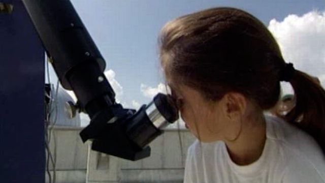 Fillette observant dans un télescope astronomique en 1995 en Valais à St-Luc. [RTS]