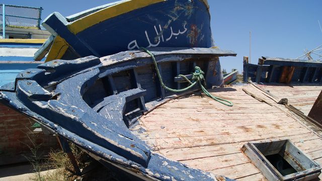 Le long du port touristique de Lampedusa, un terrain vague a été transformé en cimetière de bateaux où s’entassent les embarcations utilisées par les migrants pour arriver sur les rives européennes de la Méditerranée. [Cécile Debarge]