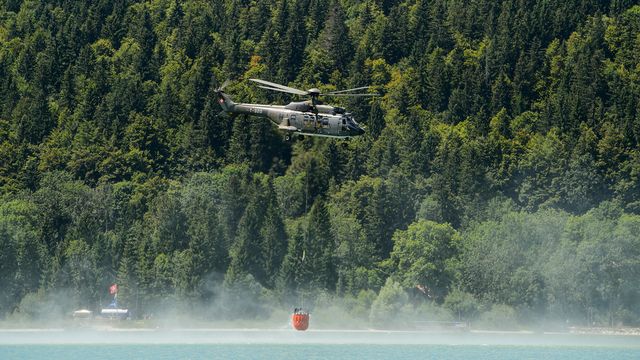 Un hélicoptère Super Puma des forces aériennes puise dans l'eau, ici en Suisse. [Jean-Christophe Bott - Keystone]