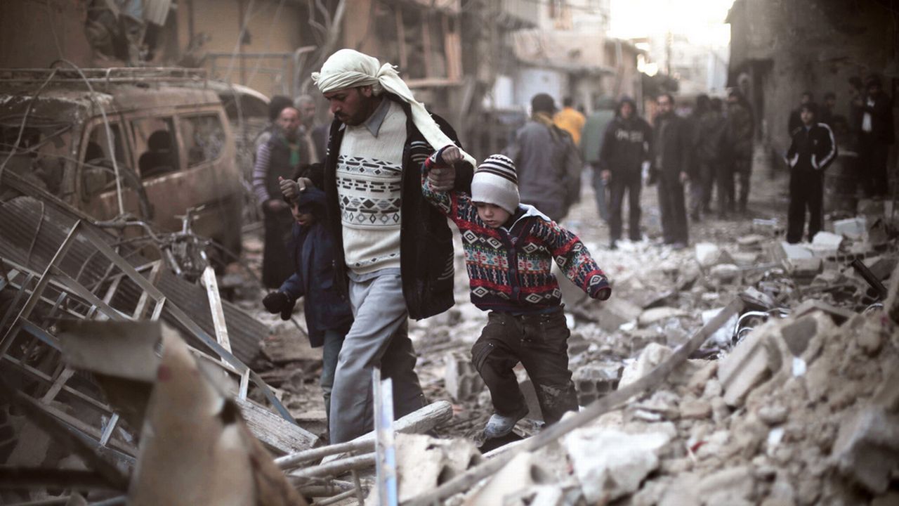 Un homme marche avec des enfants dans les ruines de Ghouta, dans l'est de la Syrie. [Save the Children via AP - Keystone]