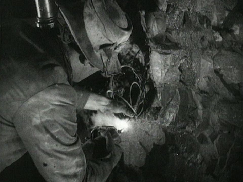 Ouvrier allumant mèche de dynamite dans un tunnel. [RTS]
