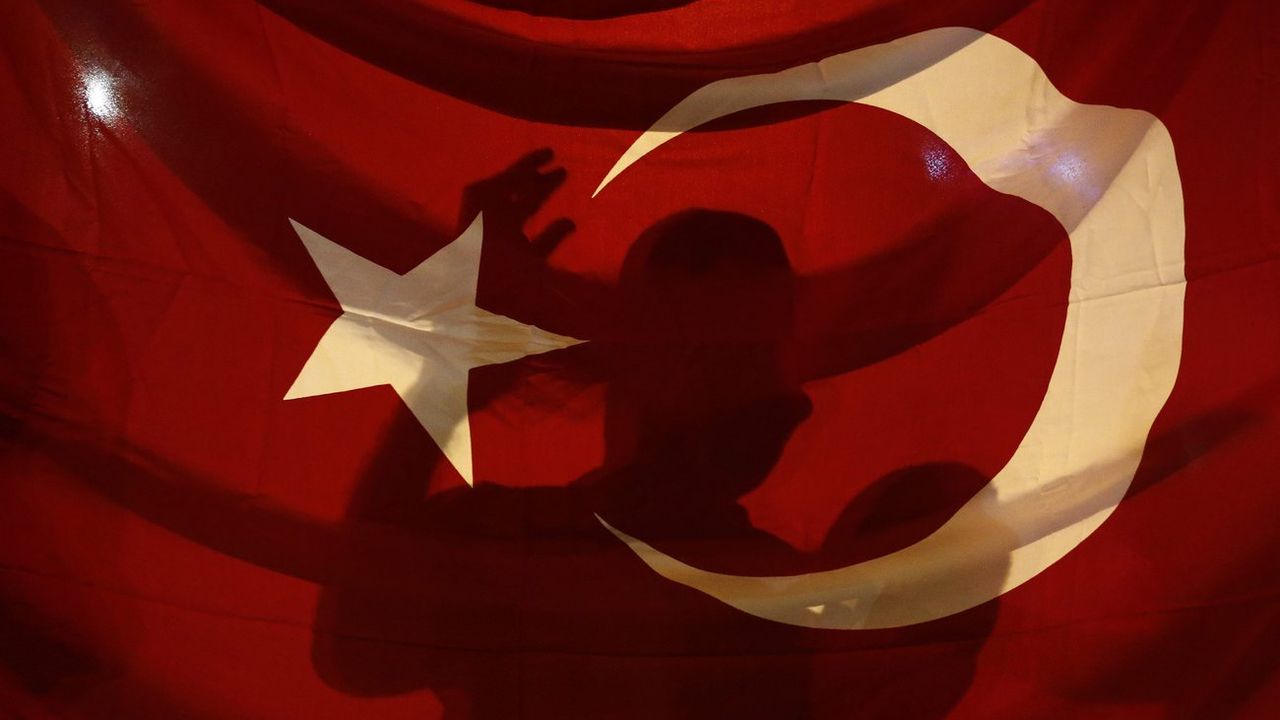 Une ombre derrière un drapeau de la Turquie. [SEDAT SUNA - KEYSTONE]