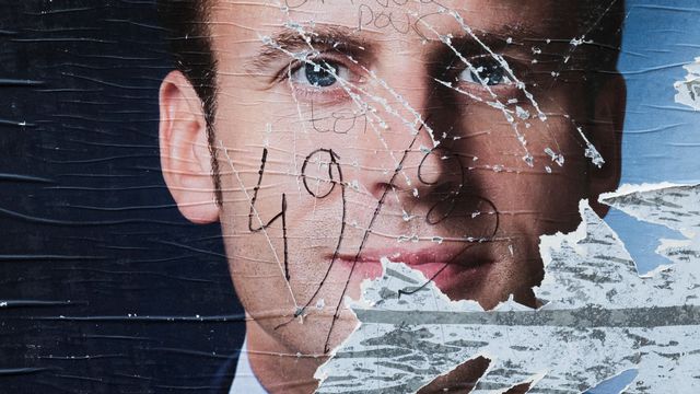 Une affiche déchirée et taguée représentant le candidat à la présidentielle française Emmanuel Macron. [Joël Saget - AFP]