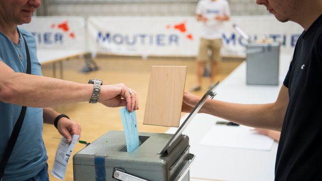 Un votant glisse son bulletin dans l'urne du bureau de vote de Moutier [Jean-Christophe Bott - Keystone]