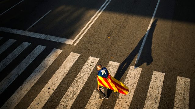 Un homme portant le drapeau de la Catalogne sur ses épaules à Barcelone. [Francisco Seco - AP/Keystone]