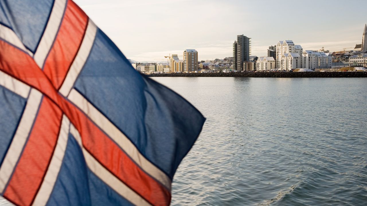 Un drapeau islandais flotte avec Reykjavik, la capitale du pays, en arrière-plan. [Stuart Westmorland - AFP]