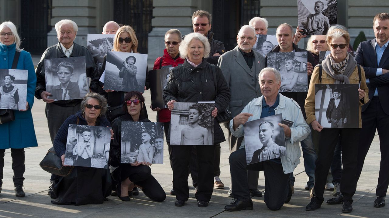 Des enfants placés posent avec une photo d'eux devant le Palais fédéral en mars 2014. [Lukas Lehmann - Keystone]