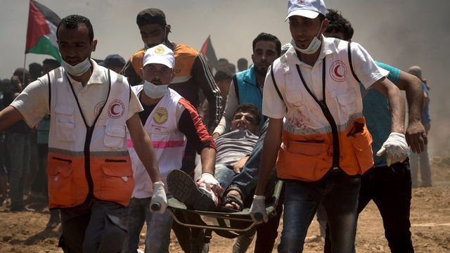 Des médecins portent un homme blessé par balle durant une manifestation à la frontière de Gaza, lundi 14 mai, jour de l'inauguration de l'ambassade américaine à Jérusalem. [LUCA PIERGIOVANNI - keystone]