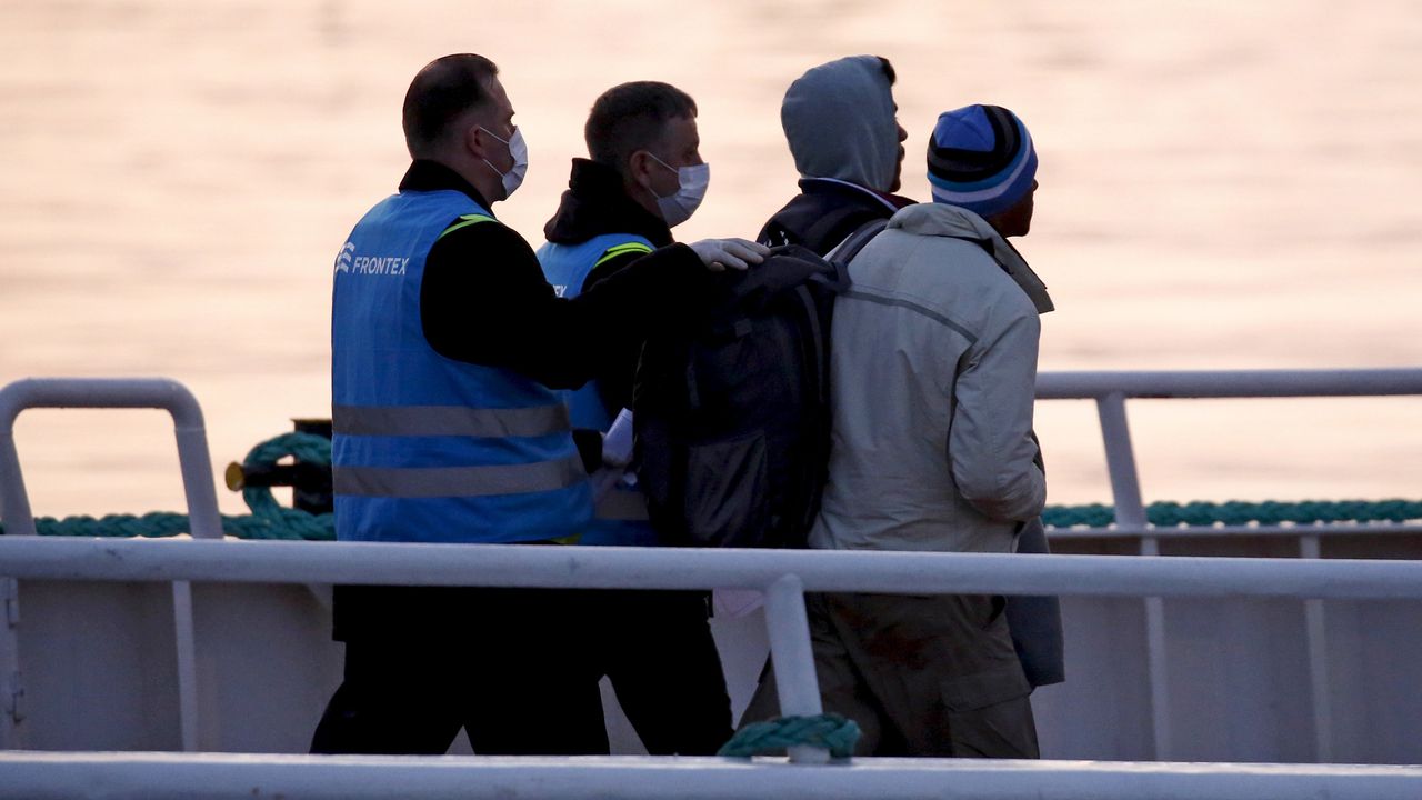 Des gardes-frontière de l'agence européenne Frontex escortent des migrants. [Giorgos Moutafis - Reuters]