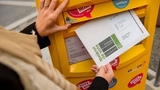 Une personne glisse un bulletin de vote dans une boite aux lettres lors de l'opération "Easyvote" pour inciter les jeunes à voter en 2015. [Jean-Christophe Bott - Keystone]