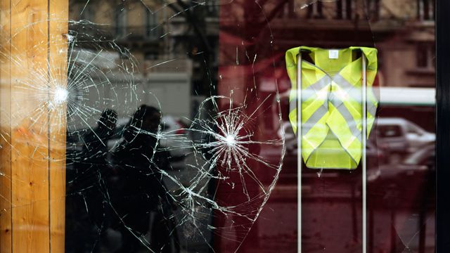 Une vitrine brisée affichant un gilet jaune, en soutien au mouvement de contestation. [Kamil Zihnioglu - AP Photo / Keystone]