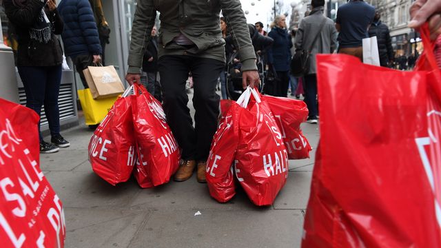 Des passants à Oxford Street, à Londres, les mains pleines de sacs après avoir profité des soldes du Boxing Day. [Andy Rain/EPA - Keystone]