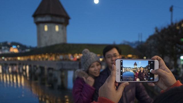 Des touristes asiatiques photographiés devant le pont de Lucerne. [Urs Flueeler - Keystone]