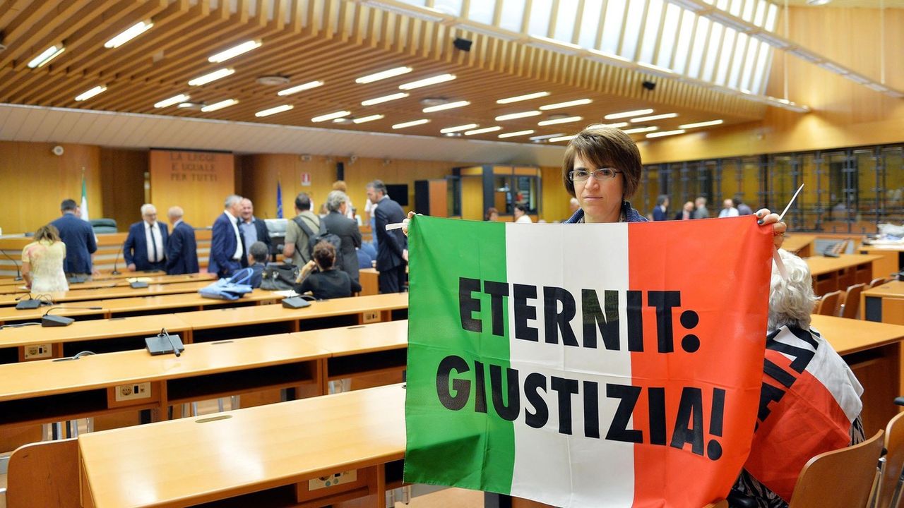 Une personne proche d'une des victimes de l'amiante tient un drapeau sur lequel est inscrit "Eternit: justice" lors du procès à Turin de Stephan Schmidheiny en 2015. [Keystone]