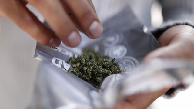 Un consommateur prépare son mélange de cannabis en vue de fumer un joint. [Rebecca Blackwell - AP/Keystone]