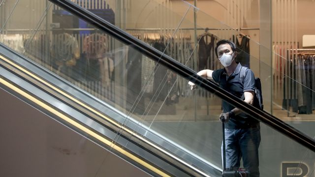 Un touriste portant un masque de protection à l'aéroport de Singapour.  [Wallace Woon - Keystone]