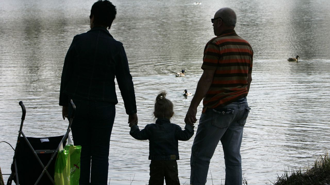 Des grand-parents et leur petite-fille au bord d'un lac. [Thomas Kienzle - AP/Keystone]