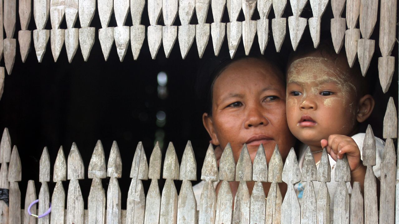 Une femme et son enfants à la fenêtre de leur maison à Nyaung Tone. Birmanie, mai 2011. [Khin Maung Win - Keystone/AP photo]