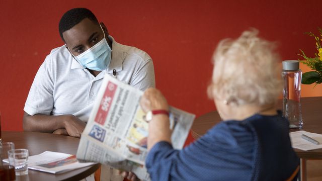 Un soldat des troupes sanitaires de l'armée suisse en discussion avec une personne âgée dans un établissement médico-social. [Laurent Gillieron - Keystone]