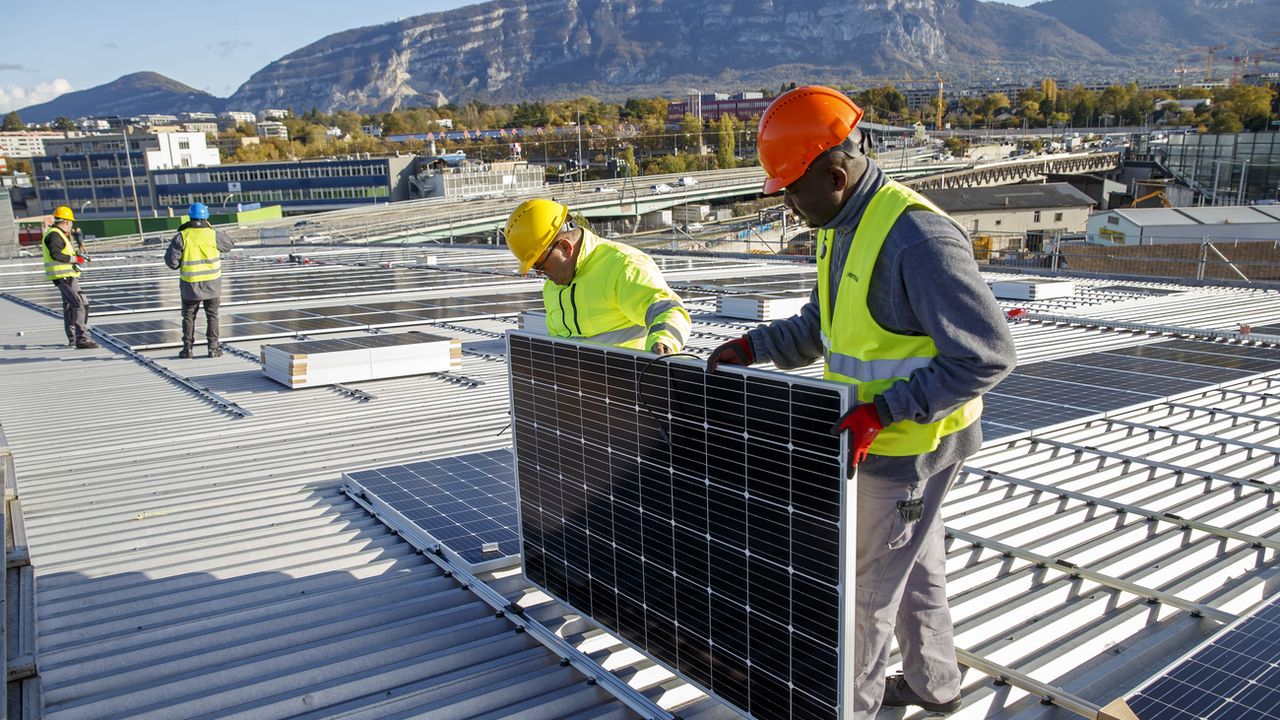 Des ouvriers posent des panneaux solaires sur le toit du stade de Genève, le 12 novembre 2019. [Salvatore Di Nolfi - Keystone]