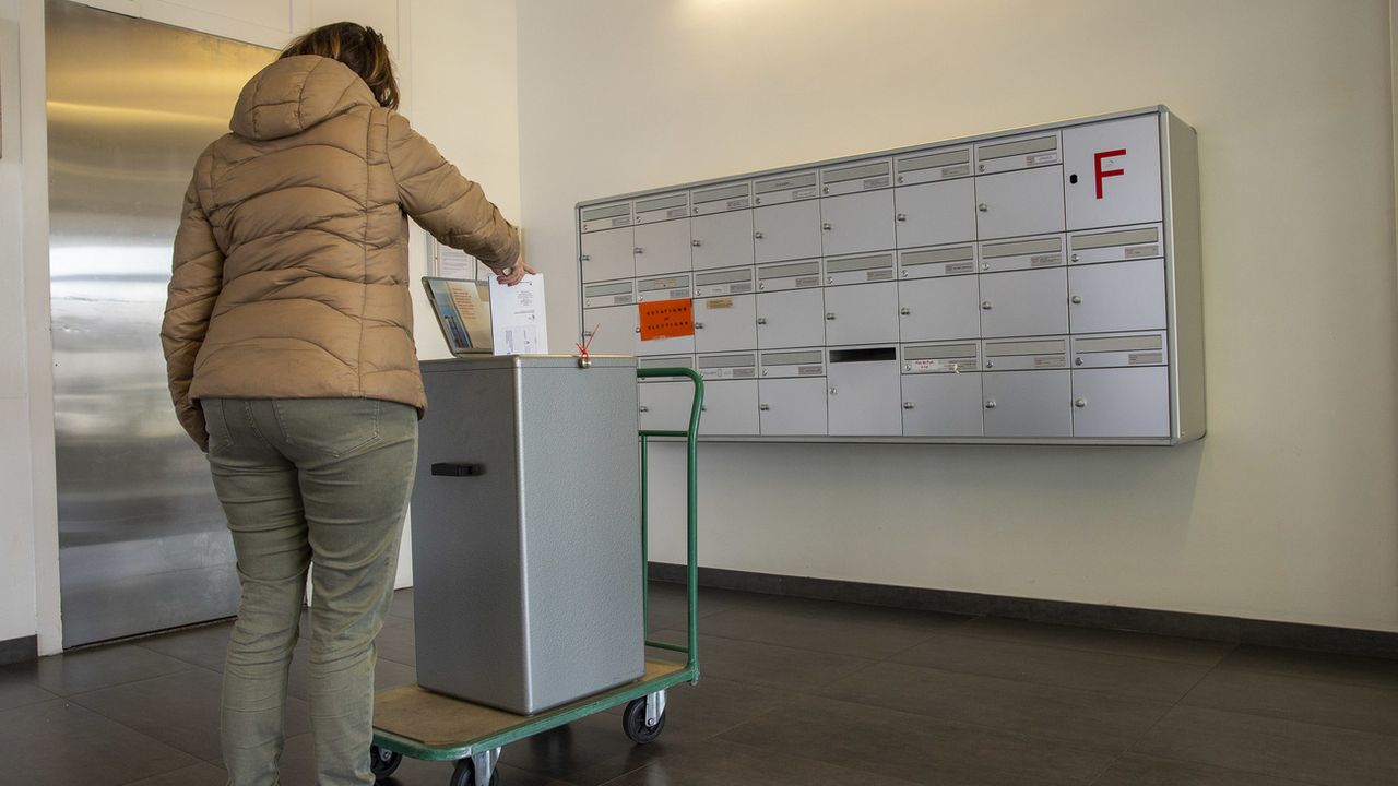 Une personne met son enveloppe dans la boîte aux lettres du Service des votations et élections de la Chancellerie, Genève, mars 2020. [Salvatore Di Nolfi - Keystone]