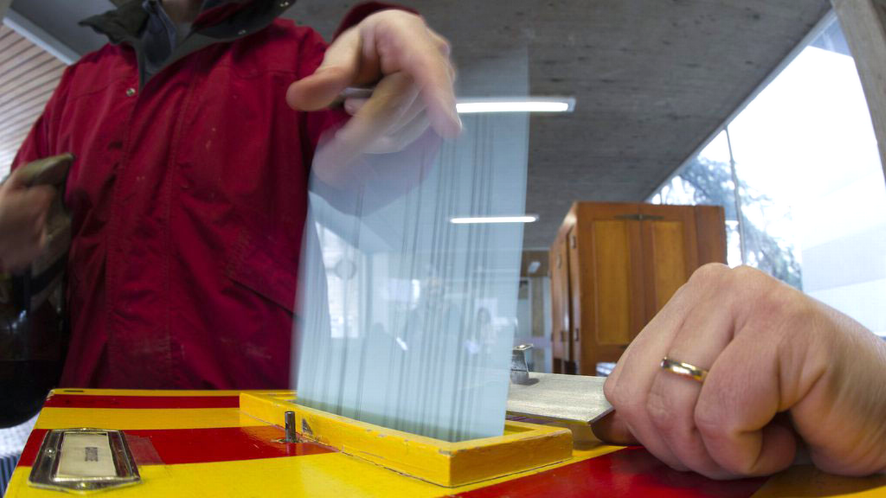 Une citoyenne met son bulletin de vote dans l'urne à Carouge (GE), lors des votations fédérales et cantonales du 11 mars 2012. [Salvatore Di Nolfi - Keystone]