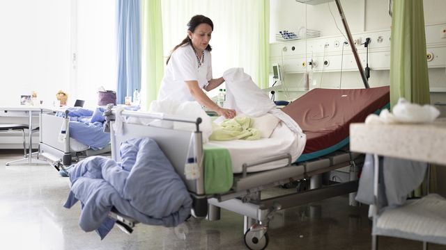 Une infirmière défait un lit à l'hôpital de l'Ile à Berne, le 21 novembre 2018. [Gaetan Bally - Keystone]