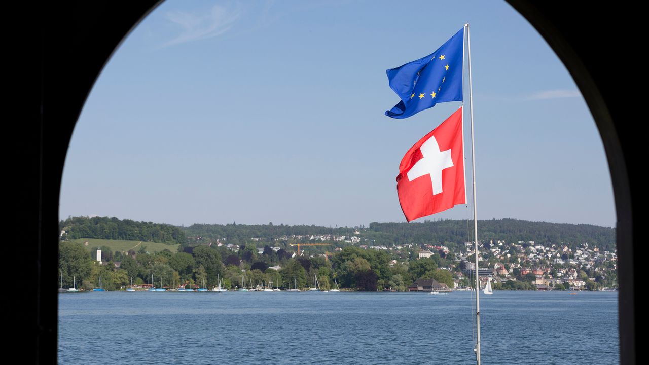 Un drapeau européen et un drapeau suisse flottent dans le vent au bord du lac de Zurich. [Gaëtan Bally - Keystone]