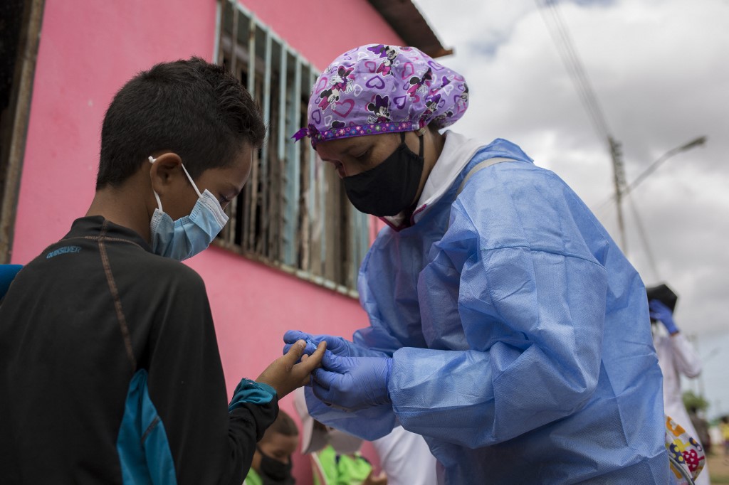 Une volontaire de Médecins Sans Frontières exécute un test pour la malaria sur un jeune patient à Barcelona, au Venezuela (2021).