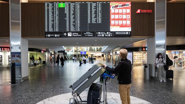 Un homme regarde le tableau des départ dans l'aéroport de Zurich le 1er avril 2021. [Alexandra Wey - Keystone]