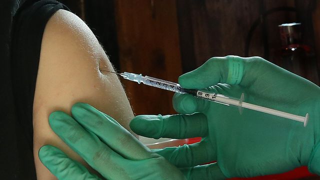 Une jeune femme reçoit un vaccin contre le coronavirus. [Wolfgang Kumm - Keystone/DPA]