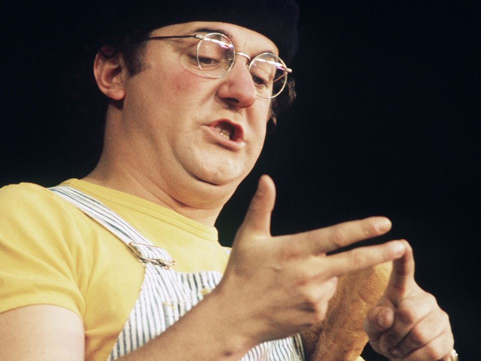 Le chansonnier-fantaisiste Coluche, vêtu de sa traditionnelle salopette rayée sur la scène de l'Olympia en 1975. [AFP]
