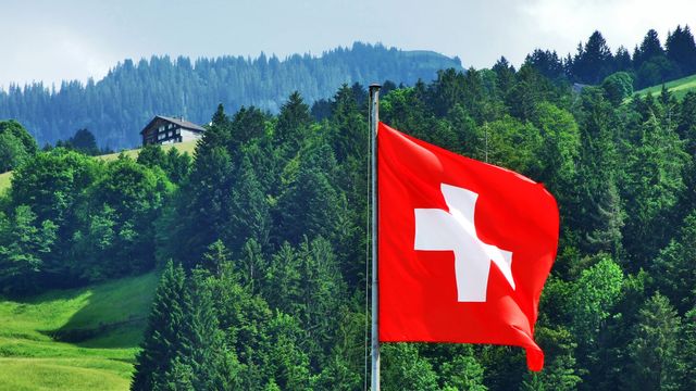 Un drapeau suisse vole au vent dans la montagne. [MarioKrpan - Depositphotos]
