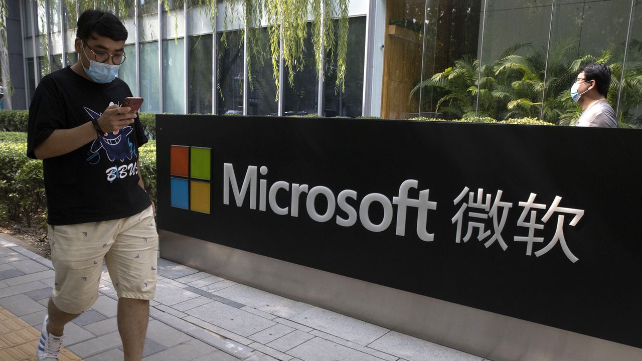 Un homme regarde son téléphone devant le siège de Microsoft à Pékin. [Ng Han Guan / AP Photo - KEYSTONE]