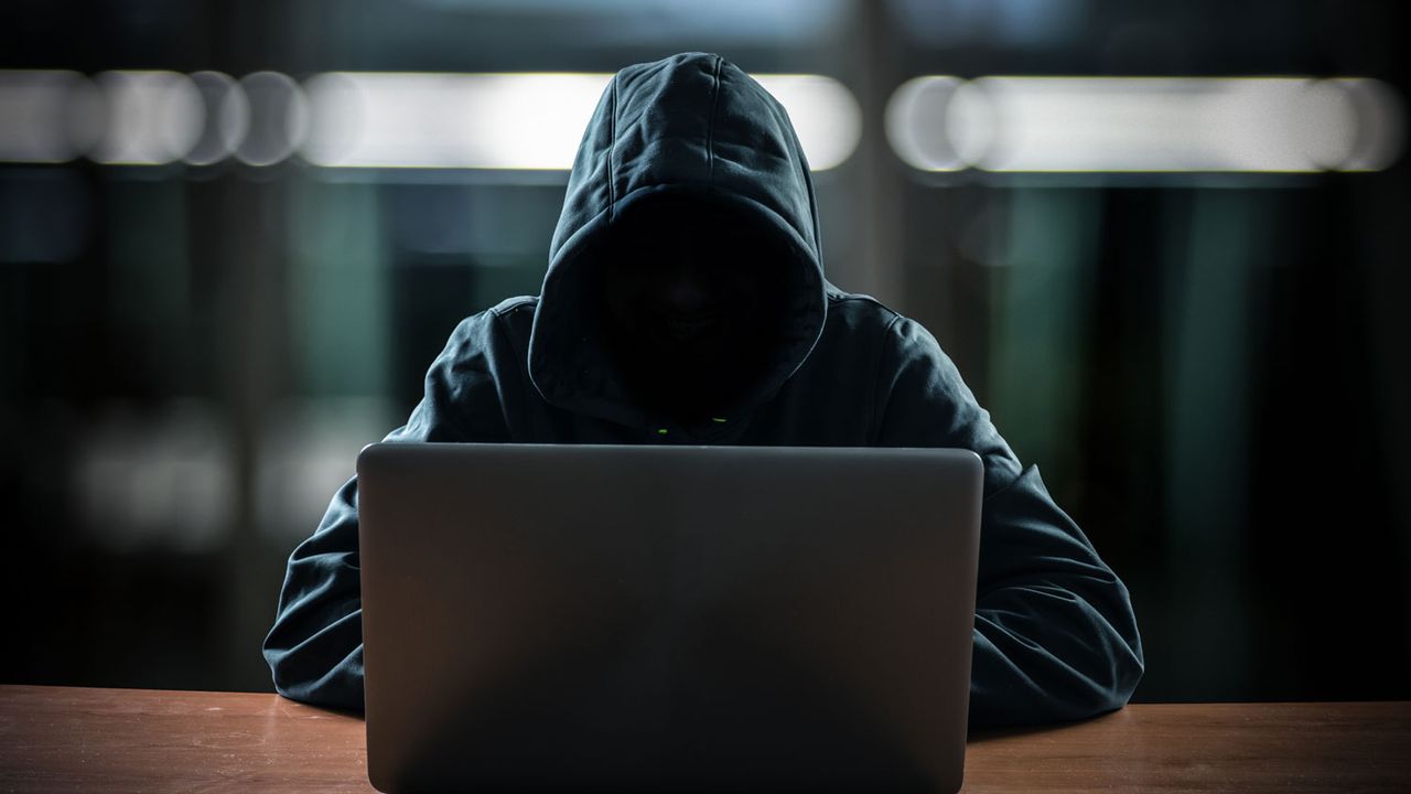 Un hacker se tient derrière son écran d'ordinateur. [minervastock - Depositphotos]