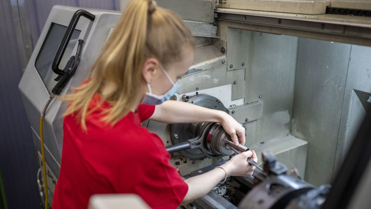 Une apprentie monte une pièce dans une machine, le 15 avril 2021 dans l'atelier de mécanique de la LBB à Bâle. [Christian Beutler - Keystone]