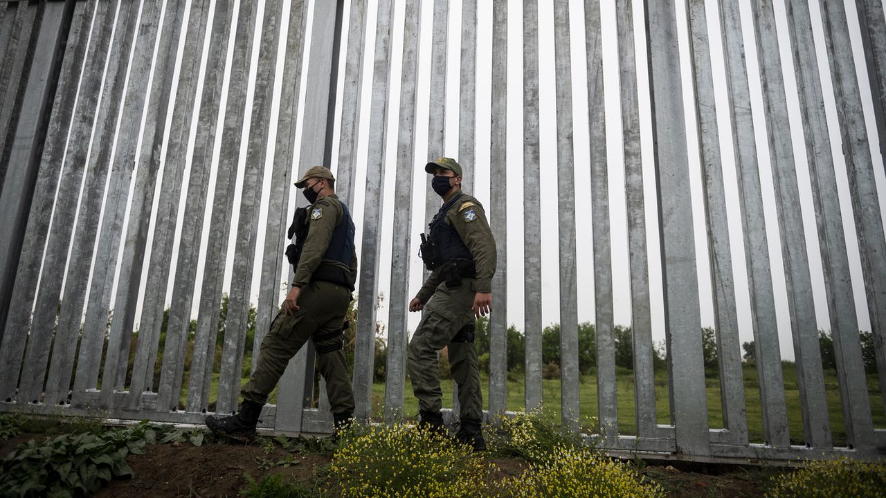 Des policiers patrouillent le long d'un mur à la frontière entre la Grèce et la Turquie. [Giannis Papanikos - AP Photo]
