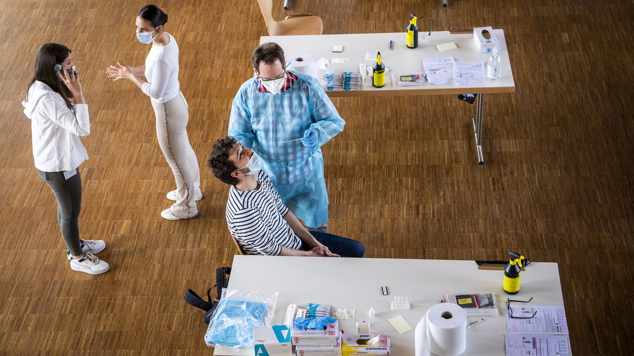 Des personnes font un test Covid dans un centre de dépistage au Mont-sur-Lausanne. [Jean-Christophe Bott - Keystone]