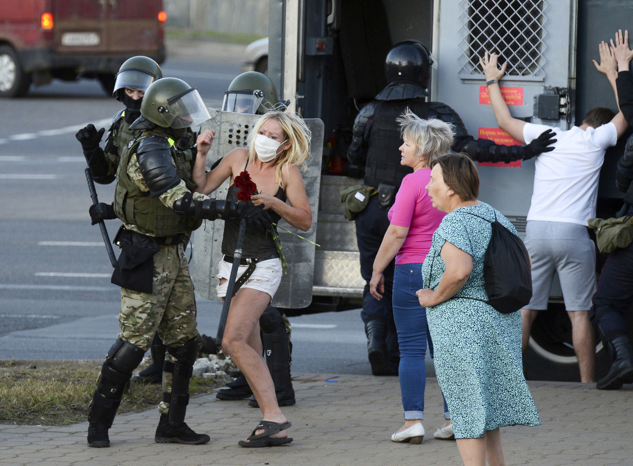 Une jeune femme armée d'un bouquet de fleurs aux prises avec un policier anti-émeute à Minsk, capitale de la Biélorussie, le 11 août 2020. Lorsque les Biélorusses ont protesté, le 9 août, contre ce qu'ils ont appelé une élection frauduleuse, la police a sévèrement réprimé les manifestations. Au pouvoir depuis 1994, le président Alexandre Loukachenko s'est efforcé de mettre un terme aux manifestations par de vagues promesses de réformes mêlées à des menaces, des convocations en justice et l'emprisonnement sélectif de militants de premier plan.