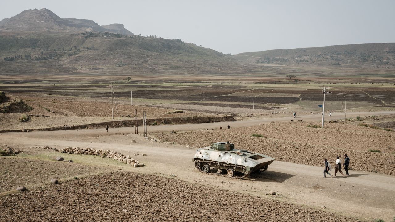 Des gens marchent près d'un char de l'armée éthiopienne abandonné sur la route près de Dengolat, au sud-ouest de Mekele dans la région du Tigré, en Éthiopie. [Yasuyoshi Chiba - AFP]