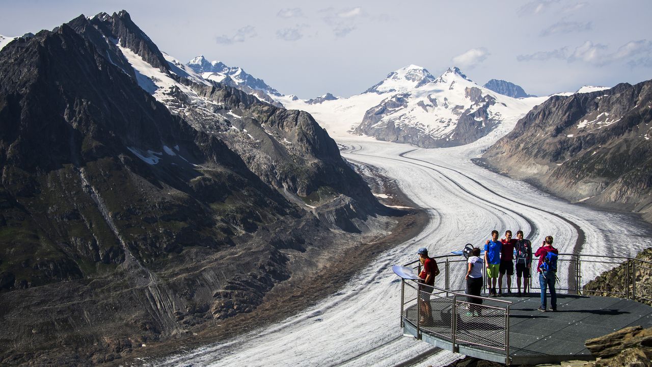 Des personnes observent le glacier d'Aletsch depuis le point de vue de l'Eggishorn, le dimanche 15 août 2021 au-dessus de Fiesch. Le glacier d'Aletsch est le plus grand glacier des Alpes, situe dans le sud de la Suisse dans le canton du Valais. [Jean-Christophe Bott - Keystone]
