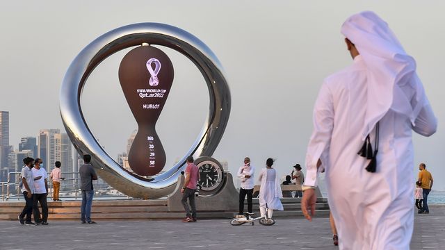 Des personnes se rassemblent devant l'horloge du compte à rebours du premier match de la Coupe du Monde de la FIFA 2022 à Doha corniche à Doha, Qatar, le 25 novembre 2021. [Noushad Thekkayil - EPA/Keystone]