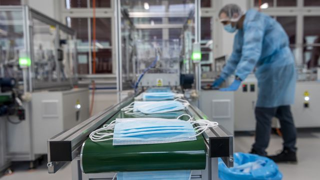 Un ouvrier contrôle la production de masques d'hygiène sur une machine de la nouvelle fabrique de masques chirurgicaux Amyna 3 lors de la crise du Coronavirus (Covid-19), le vendredi 20 novembre 2020 à Corgémont dans le Jura bernois.  [JEAN-CHRISTOPHE BOTT - KEYSTONE]