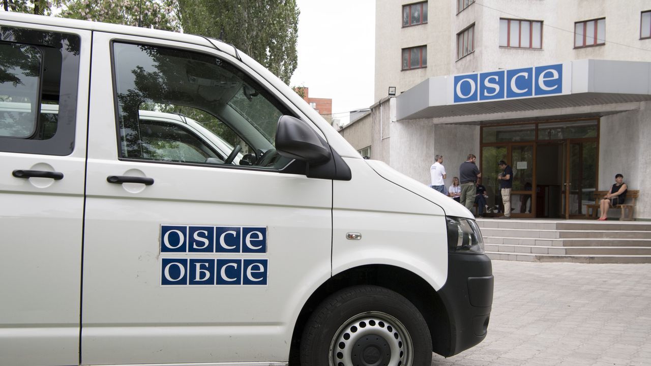 Un bus de l'OSCE photographié devant un bâtiment de l'OSCE en Urkaine.  [Anthony Anex - Keystone]
