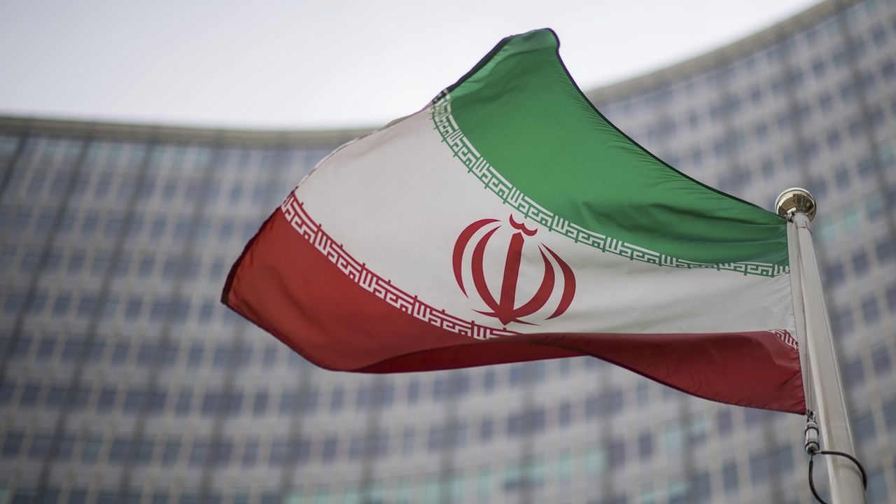 Le drapeau iranien devant le bâtiment de l'Agence internationale de l'énergie atomique. [Michael Gruber - Keystone]
