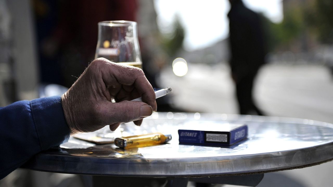Un homme fumant une cigarette sur une terrasse de Lausanne. [Dominic Favre - Keystone]