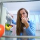 Une femme se pince le nez en ouvrant son frigo. [goffkein - Depositphotos]