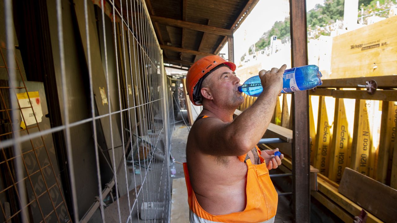 Un ouvrier sur un chantier s'hydrate pendant un épisode de canicule. [Francesca Agosta - Keystone]