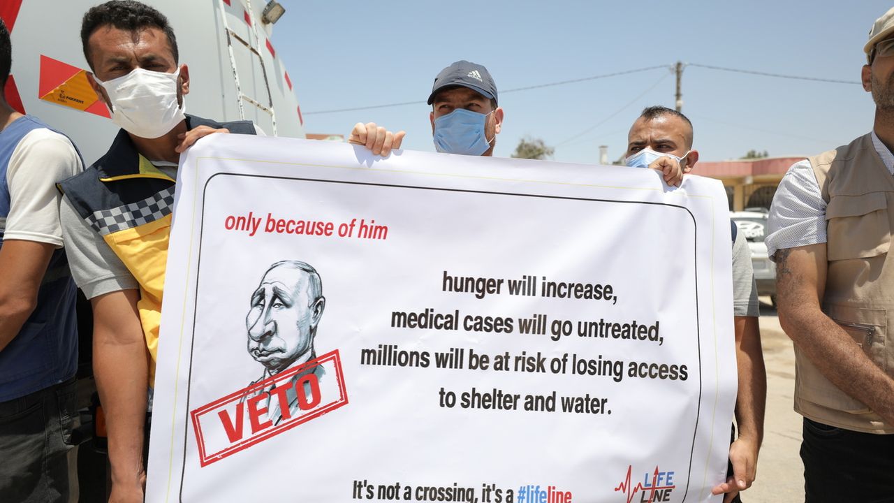Des personnes tiennent des pancartes lors d'un rassemblement appelant la communauté internationale à maintenir le corridor humanitaire transfrontalier au poste de passage de Bab Al-Hawa, à Idlib, en Syrie, le 7 juillet 2022. [Yahya Nemah / EPA - KEYSTONE]